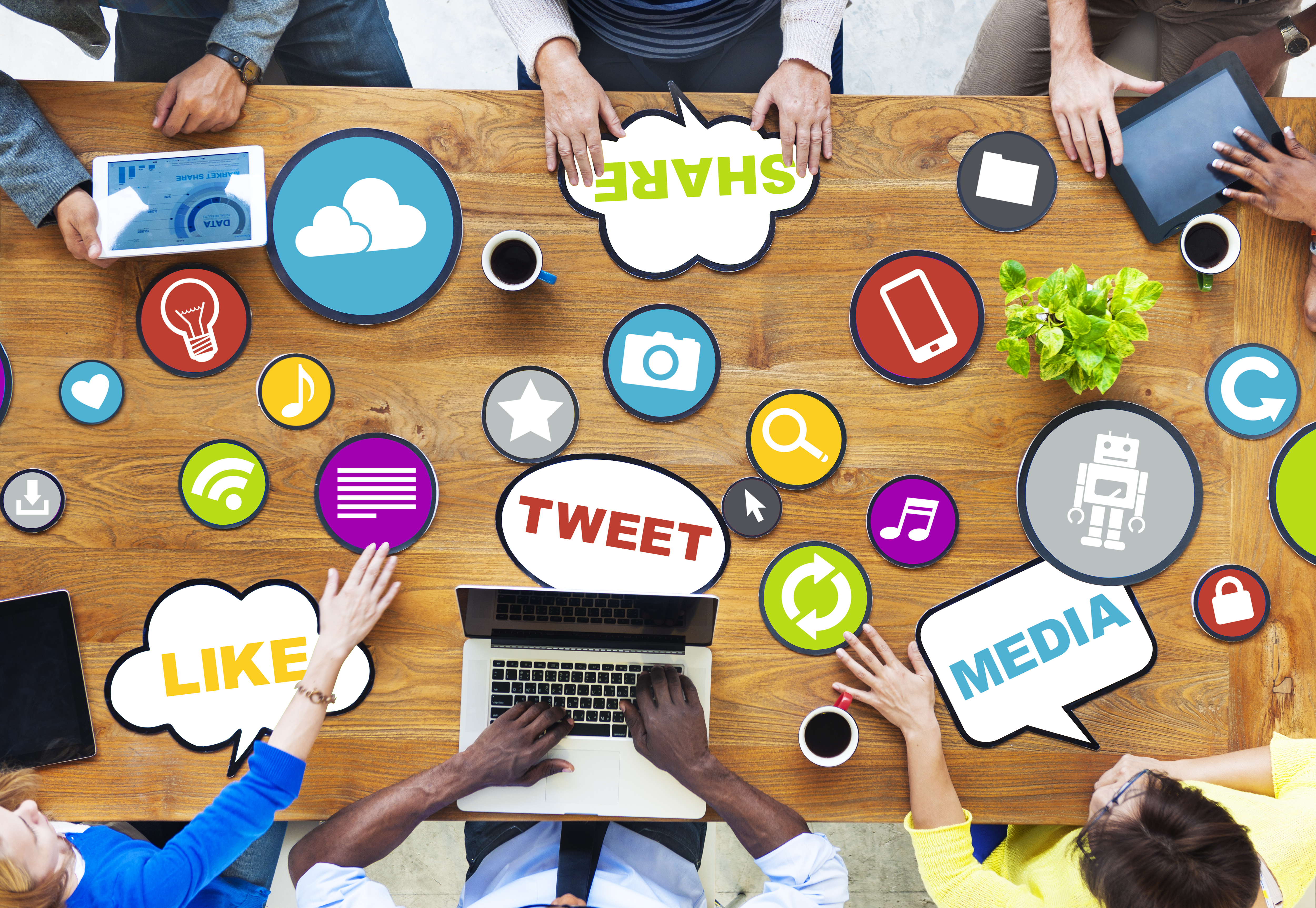 a rectangular office table surrounded by people with their laptops which seems to be generating comment bubbles that says tweet, media, like, share.